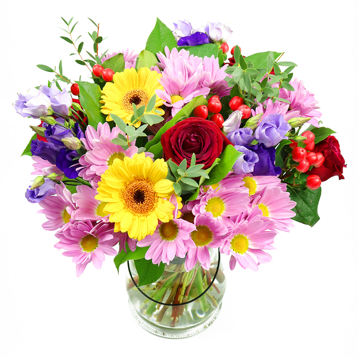 This image captures a richly composed floral arrangement standing tall in a clear glass vase, displayed against a crisp white background that highlights every detail. At the core of the bouquet, deep red roses bloom in velvety spirals, their layered petals creating a sense of depth and heartfelt emotion. Just alongside them, two striking yellow gerbera daisies, with their dark brown-orange centres, shine like warm beacons, infusing the display with an uplifting energy reminiscent of bright mornings along Gidea Park's Main Road. Encircling these central flowers is a plentiful gathering of soft pink daisies or chrysanthemums, their many fine petals radiating outward from tiny yellow centres to form a generous, cushion-like mass of colour. Threading gracefully through the pastel pinks are elegant stems of purple and lavender lisianthus, their bell-shaped blossoms in varying shades and stages of opening adding a cool, refined contrast, much like the subtle hues of evening skies over Raphael Park. Here and there, clusters of bright red hypericum berries nestle between petals, their rounded, glossy forms introducing a playful yet contemporary texture. A tapestry of greenery supports and frames the blooms, from broad, dark green leaves that ground the design to finer, lighter green sprigs that arch outward, lending the arrangement a natural, garden-fresh silhouette. The transparent vase reveals a neat bundle of stems immersed in clear water, a quiet sign of professional care and freshness. Altogether, the bouquet feels joyful and generous, perfectly suited to birthdays, congratulations, or simply bringing a burst of life to a Gidea Park home, where its harmonious blend of colour, texture, and gentle fragrance would transform a hallway table or dining room into a welcoming focal point.